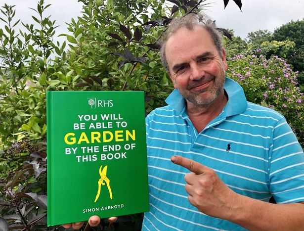 A picture of a man wearing a blue shirt and holding a green book