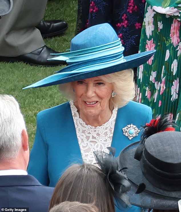 Queen Camilla, 77, looked typically elegant in a rich satin blue and white lace dress, complete with a stylish wide-brimmed hat and sensible kitten heels