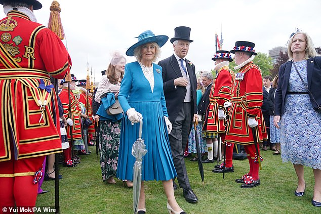 Camilla, in a teal blue crepe dress with a cream lace insert by Christian Dior, matching hat by Philip Treacy and turquoise and diamond brooch that belonged to the late Queen Elizabeth, bent down to tickle Haworth's tummy after spotting him in the crowd