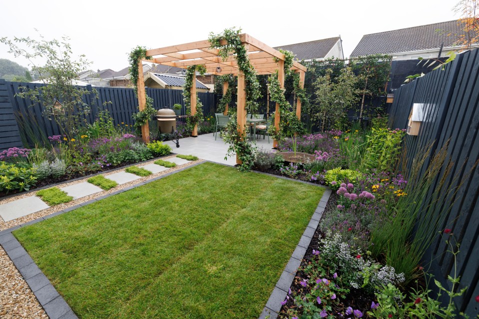 Supergarden 2024: A landscaped garden with a wooden pergola, patio, and flowerbeds.