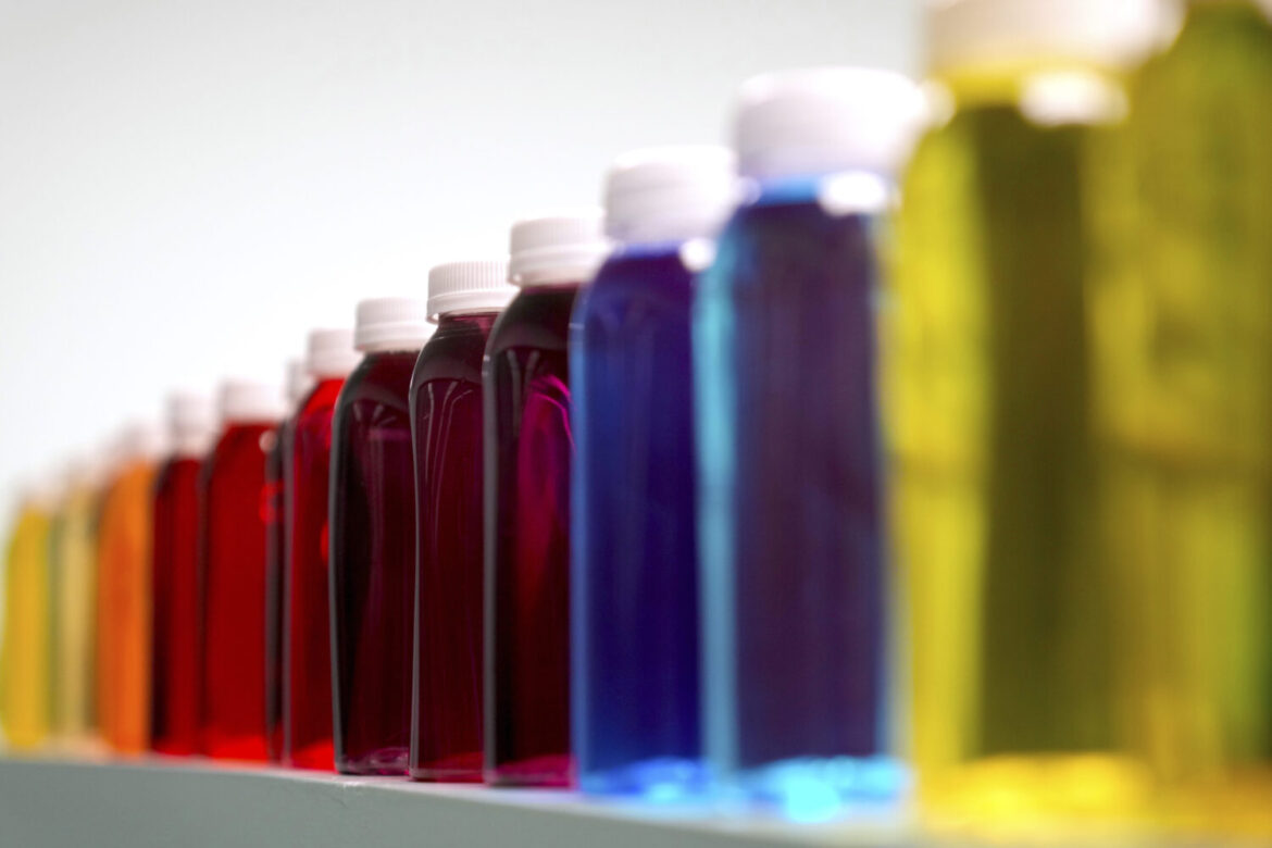 FILE - Bottles containing a variety of colored liquids sit on a shelf in a lab at Sensient Technolo...