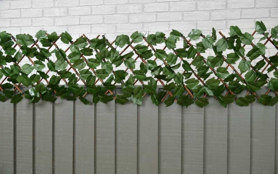 Artificial ivy leaf trellis on a gray fence.