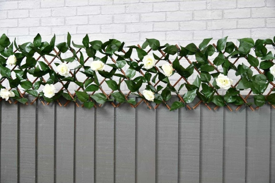 Artificial rose trellis on a gray fence.