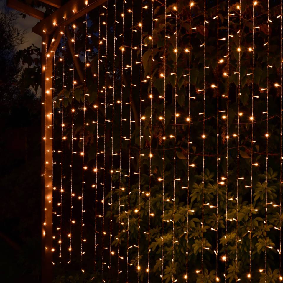 Solar-powered curtain lights illuminating a garden at night.