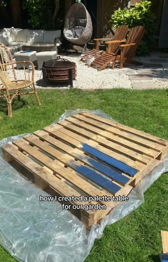 A wooden pallet being painted to make a garden table.