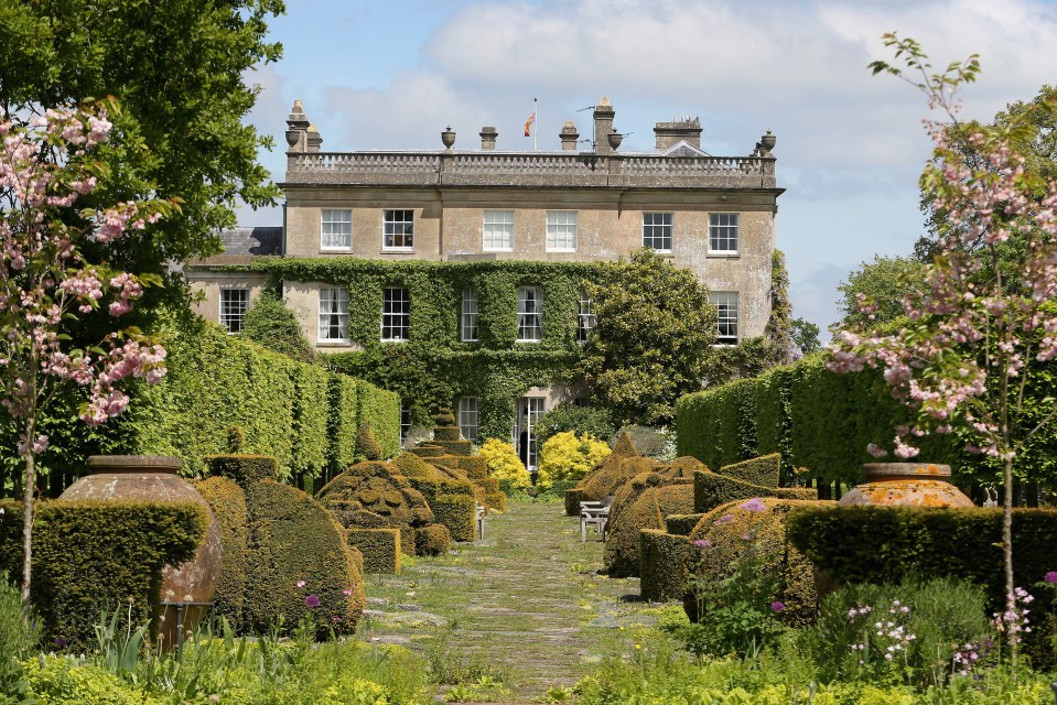 Highgrove House gardens with topiary and a stone house in the background.