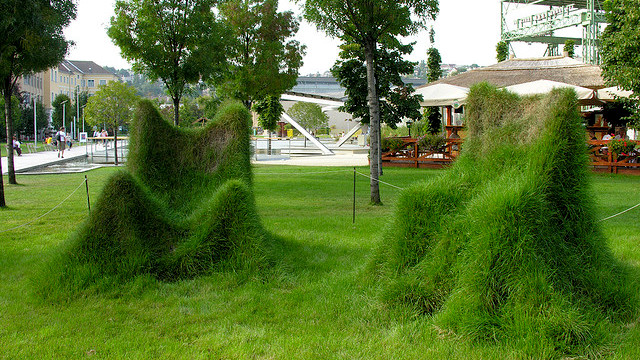 Two grass chairs in a park.