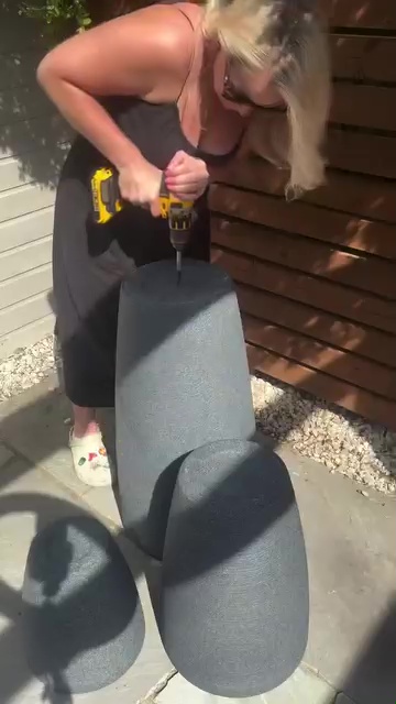 Person using a drill to assemble three gray plant pots.