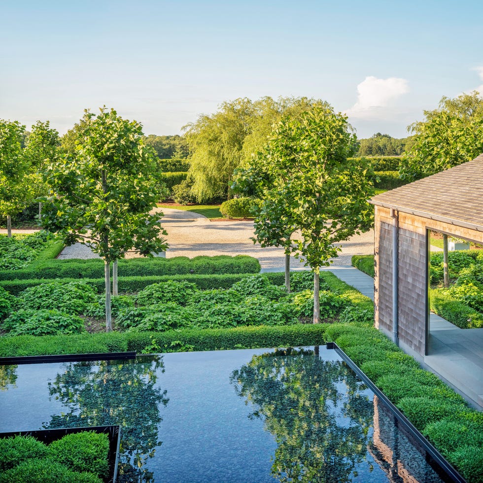 a shallow reflecting pool lined with river rock mirrors and extends the bridgehampton new york homes architecture into the surrounding landscape bridgehampton new york home pollarded plane trees give statuesque definition without obscuring views
