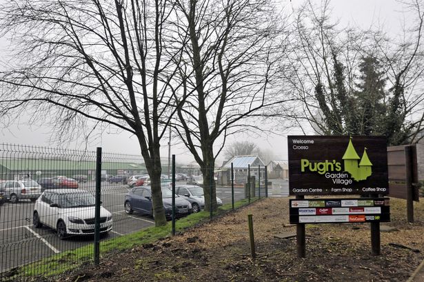 Pugh's Garden Village sign with a car park next to it 