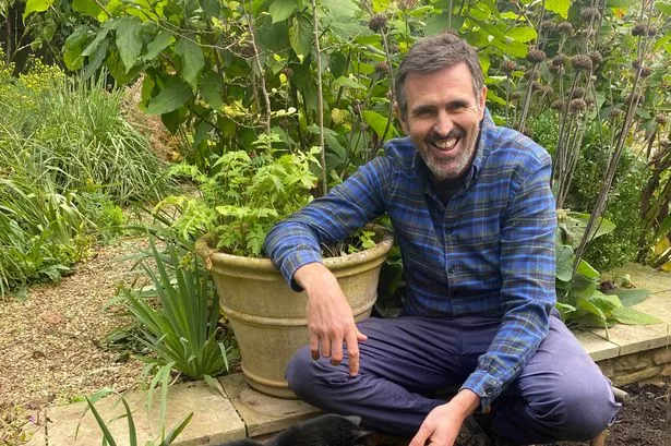 Adam Frost in his garden at home with Ash the cat