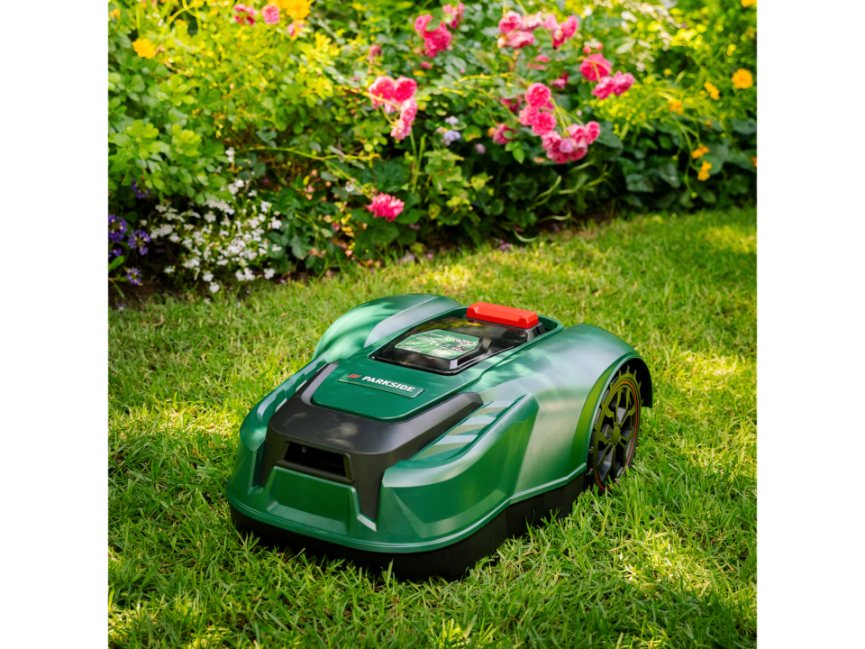 Green robotic lawnmower on a grassy lawn.