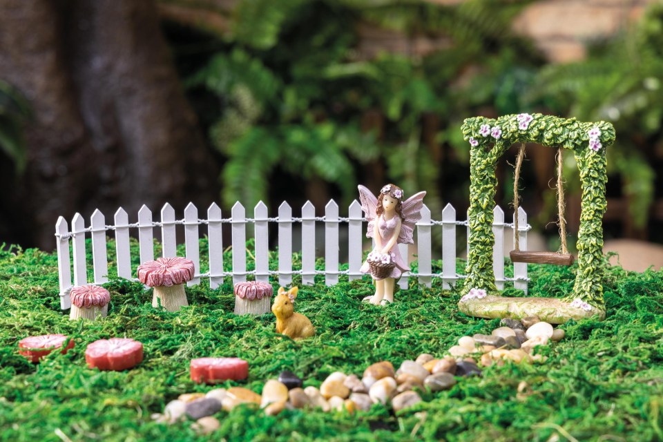 Miniature fairy garden kit with fence, swing, fairy, mushrooms, and bunny.