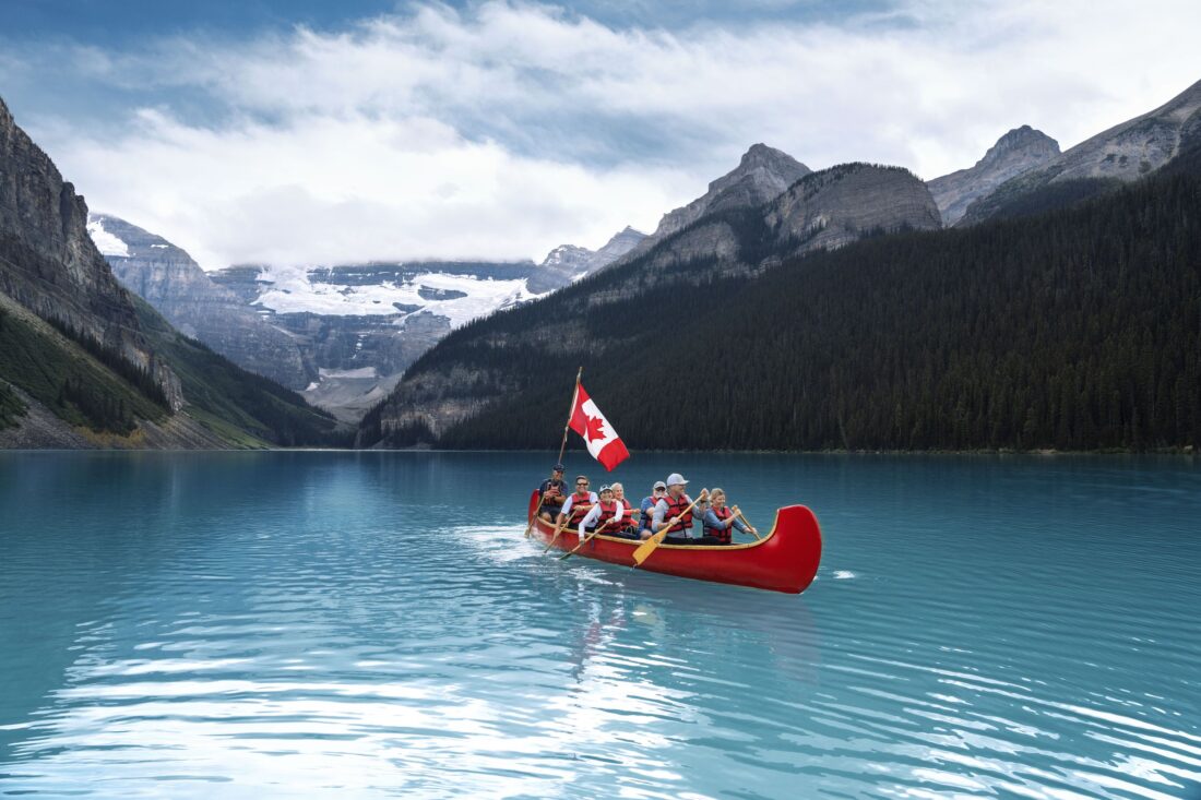 People row in a canoe in a bright blue lake
