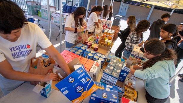 Santiago High School students fill bags with donations of food...