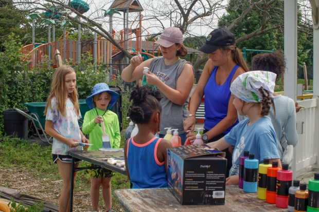Easton Urban farm summer intern Sonia Tenbarge and gardening instructor Ashley Wright open paint bottles Monday, June 30, 2025, in Easton for children to paint the gazebo in the garden. The nonprofit, which supplies fresh produce to low-income families, invited children ages 5-10 for a tour of the garden, an opportunity to pick raspberries and an art session to paint the gazebo. (Oliver Lois Economidis/The Morning Call)