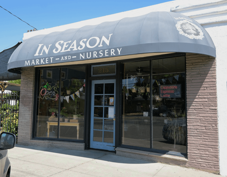 Store front on a street on a sunny day, reading "In Season."