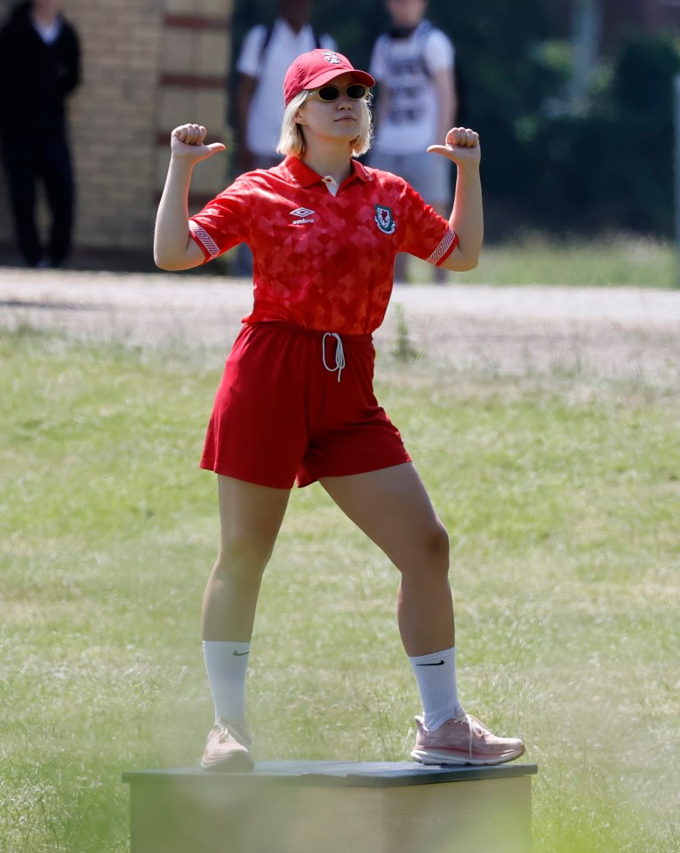 Woman in red athletic wear giving a thumbs up on a box.
