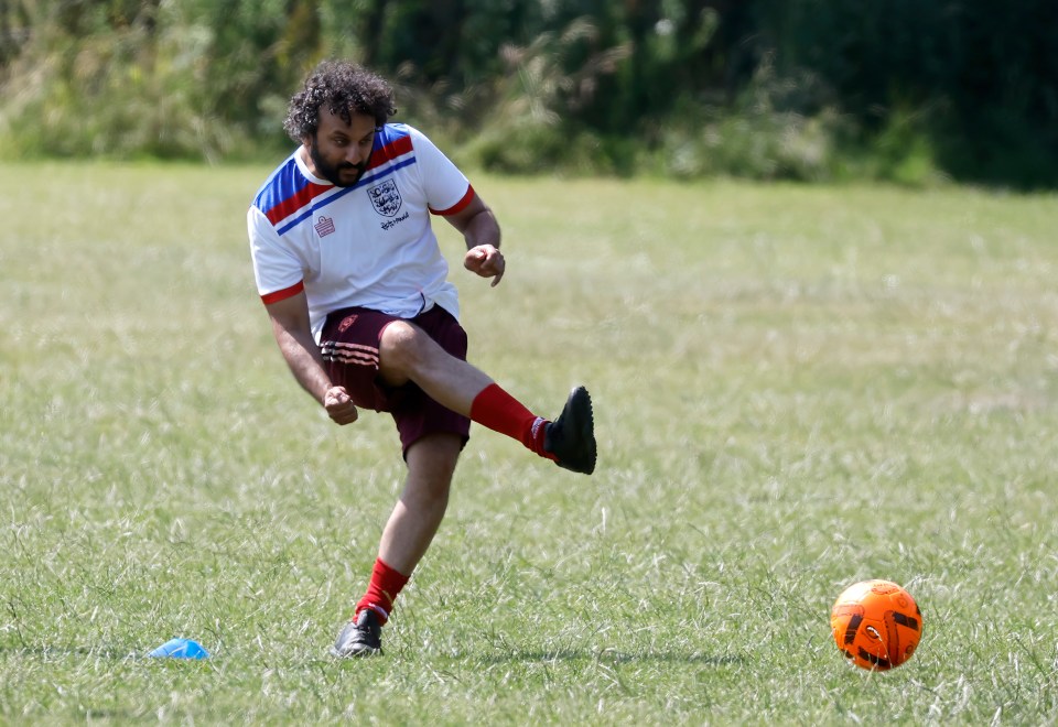 Man kicking a soccer ball on a field.