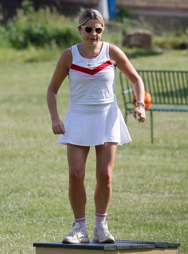 Woman in white tennis outfit standing on a platform.