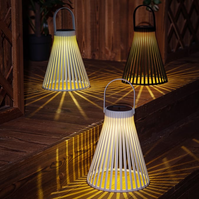 Three solar-powered lanterns on wooden steps.