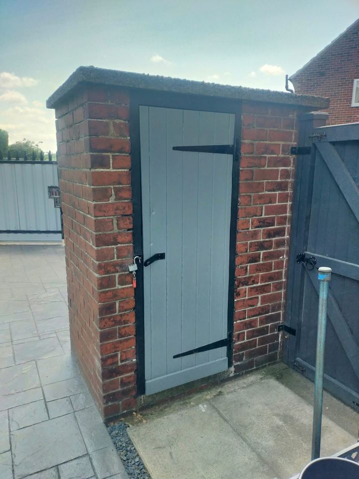 Brick outhouse with a light gray door.