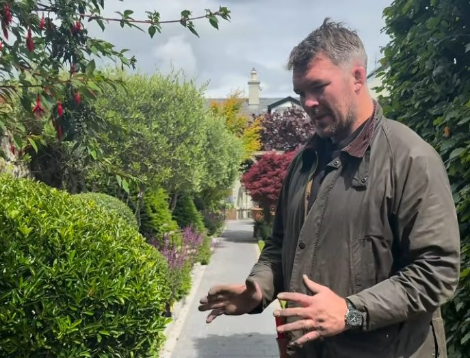 Man gesturing in a garden.