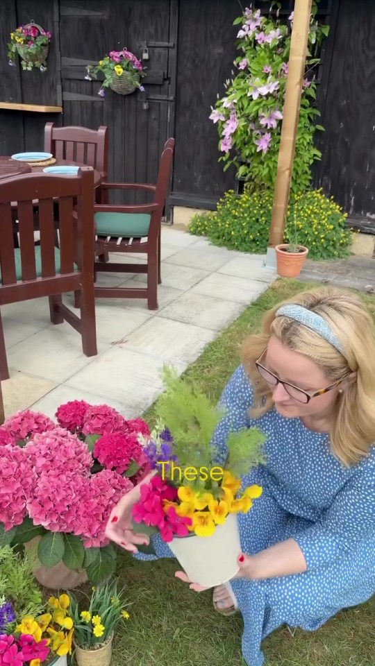 Woman arranging flowers in a garden patio.