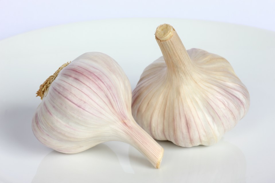 Two bulbs of garlic on a white plate.