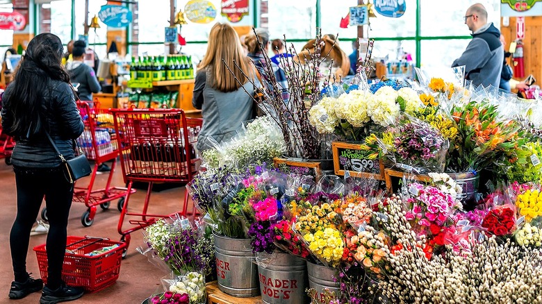 Trader Joes shoppers in line next to the store's flower selection
