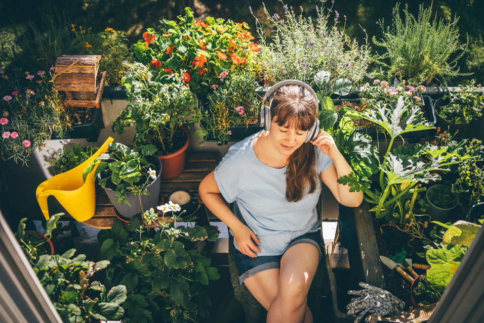 Woman listening to music surrounding by plants in her