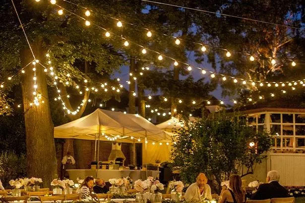 Amazon's outdoor string lights above an outdoor space with people seated at tables