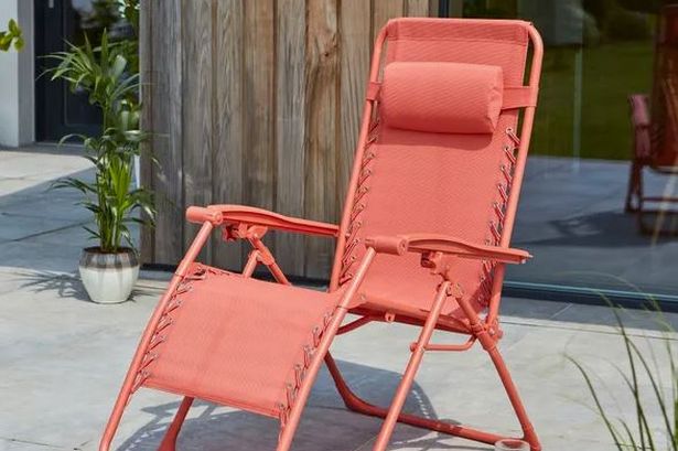 Dunelm's Helsinki Lounger in coral on a patio