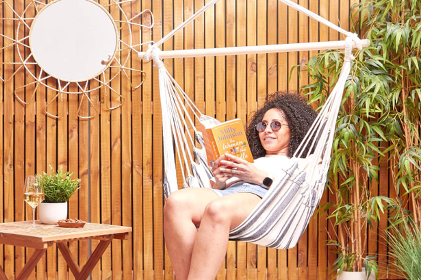 A woman sitting in the VonHaus hanging chair from Amazon