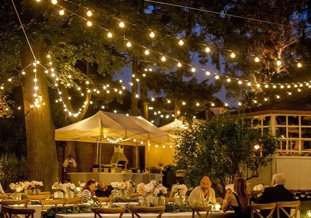 Amazon's outdoor string lights above an outdoor space with people seated at tables