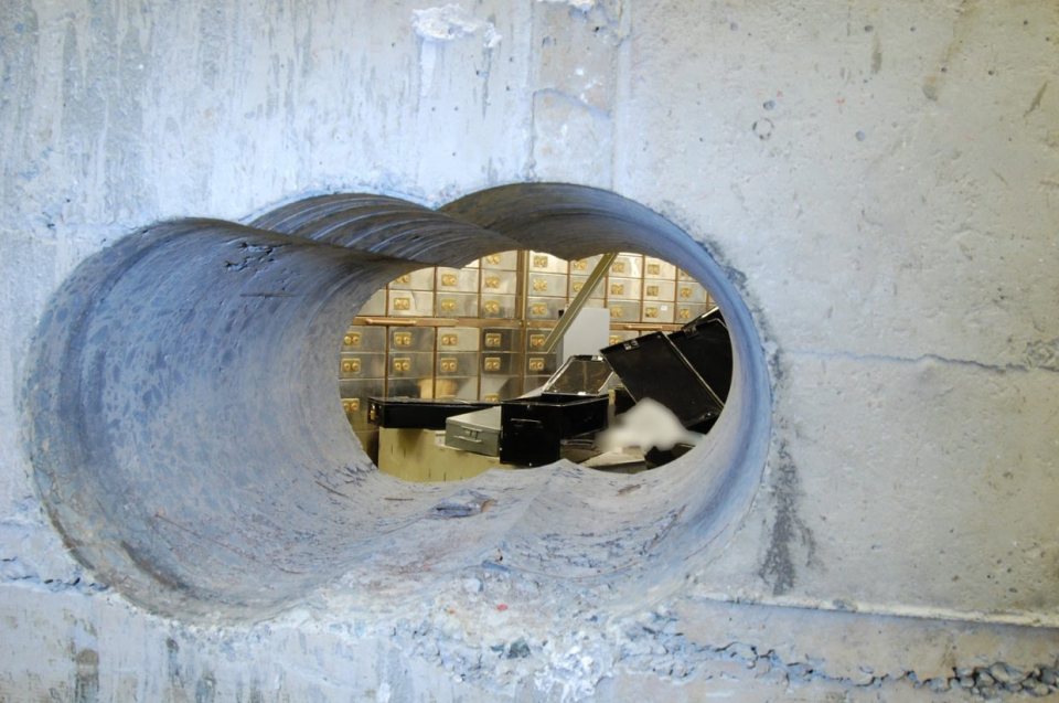 Hole drilled in a vault wall showing ransacked safety deposit boxes.