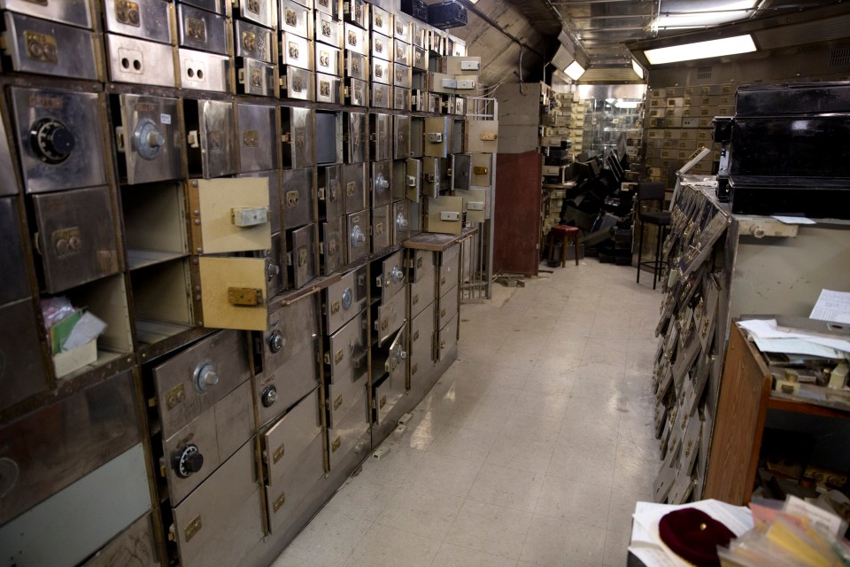 Interior of a vault with many open and closed safety deposit boxes.