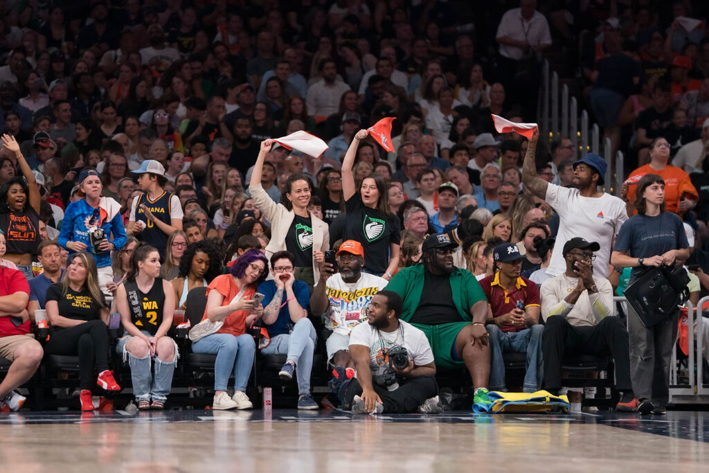 Fans move towels in the air and cheering during a WNBA game.