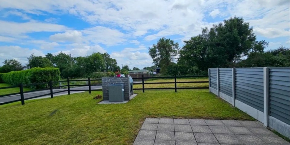 Photo of a backyard with a pizza oven and fence.
