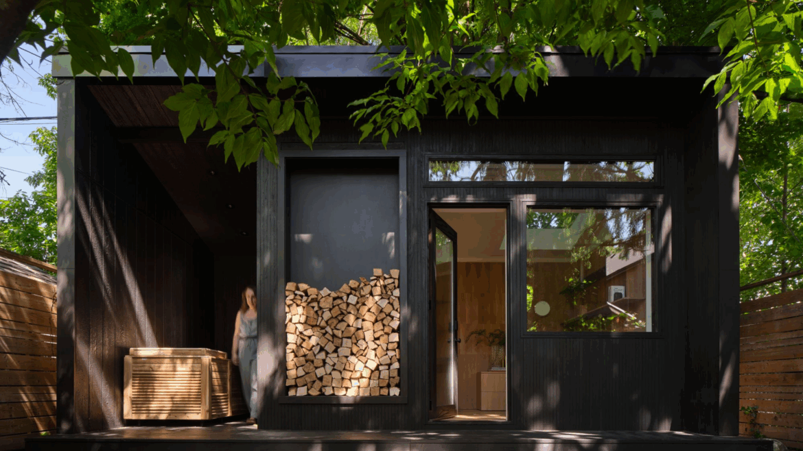 A Garden Room That Answers Work and Wellness Demands black wooden garden room in a tree filled garden with a oak clad working space, a sauna and a cold plunge