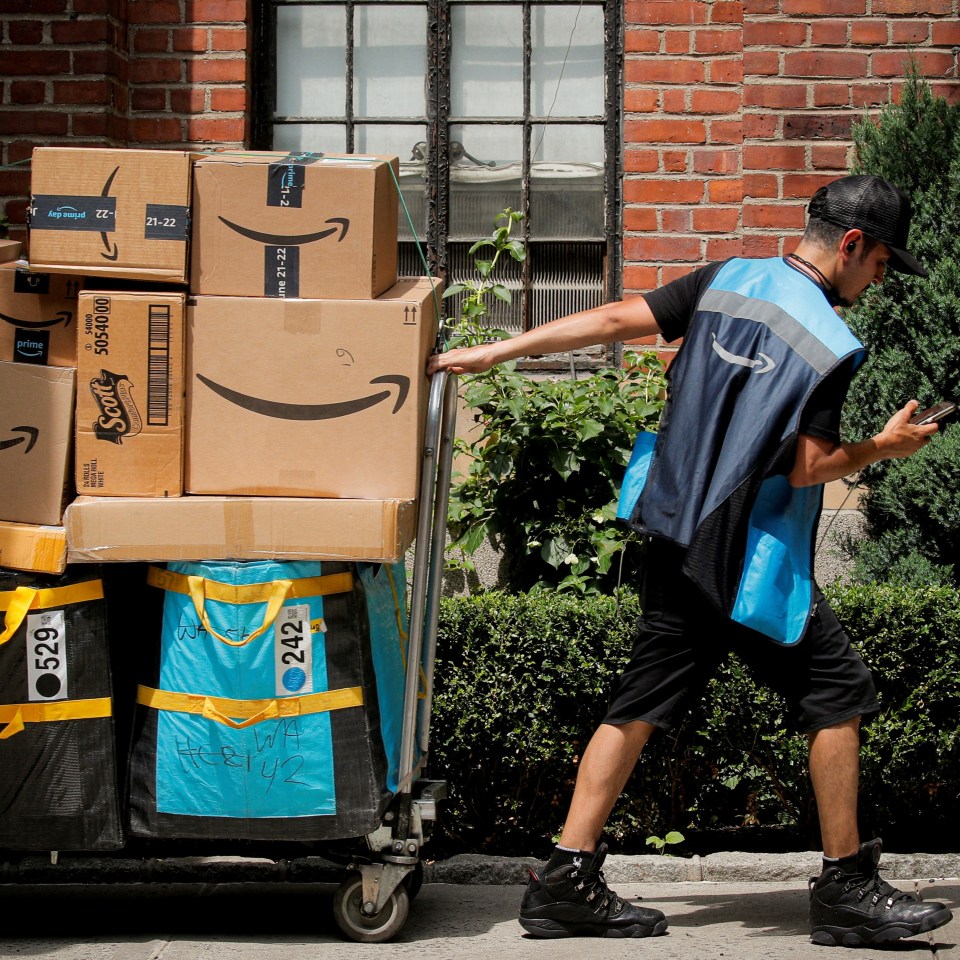 Amazon delivery worker pushing a cart of packages.