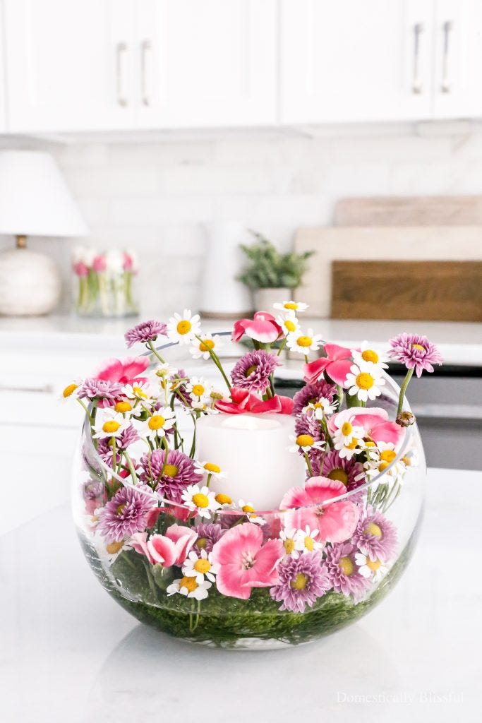 floral arrangement in a glass bowl with a white candle