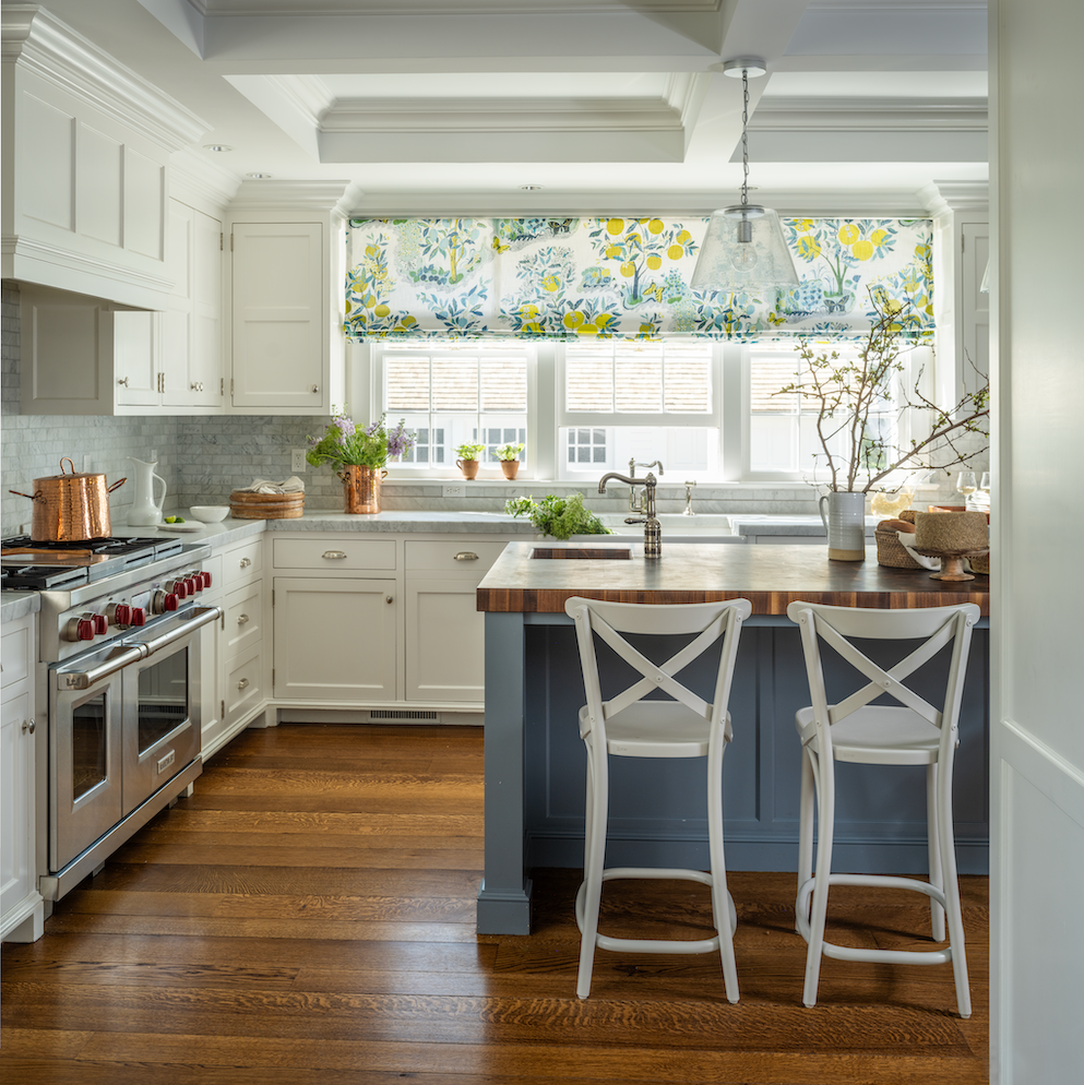 white kitchen with dark flooring and pattern roman shade