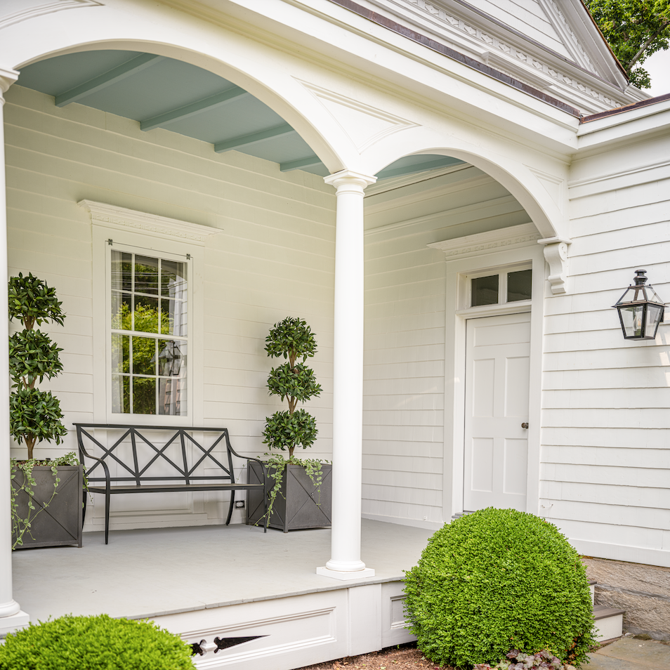 porch with bench and two planters with topiary