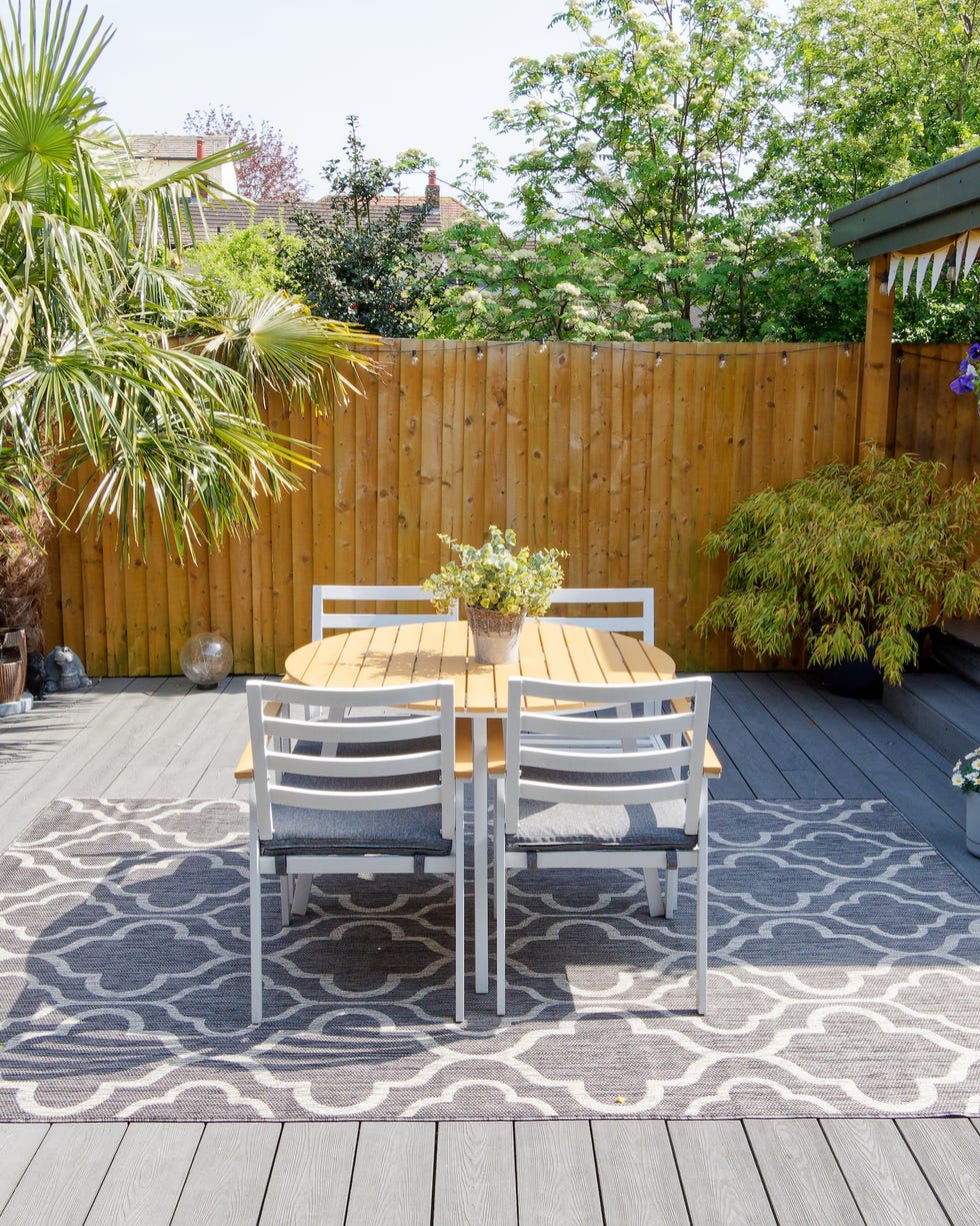 minimalistic english modern garden with table and chairs. sunny summers day with green plants and decking on the patio