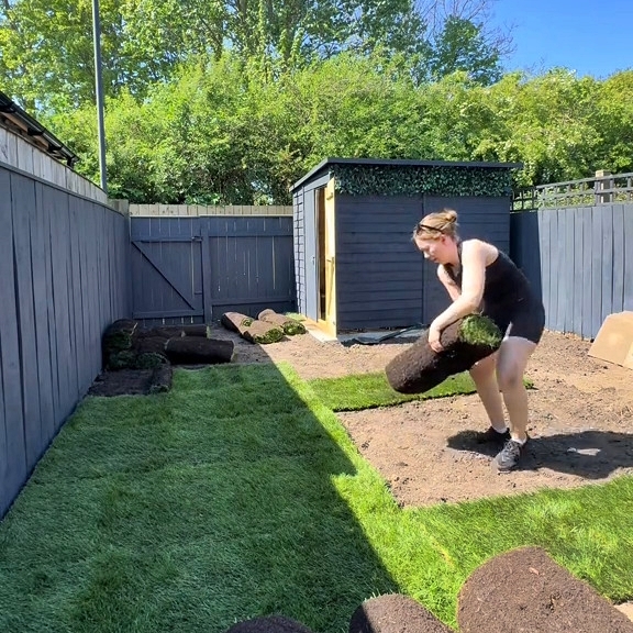 A single mother installing sod in her garden.