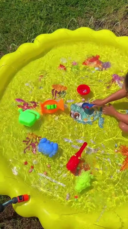 Child playing with toys in a yellow inflatable pool.