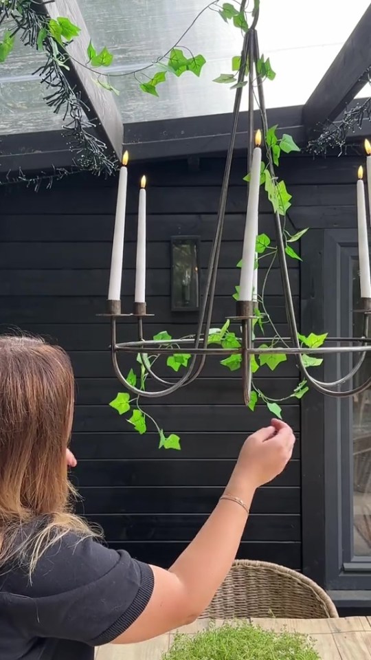 A lit candle chandelier decorated with greenery.