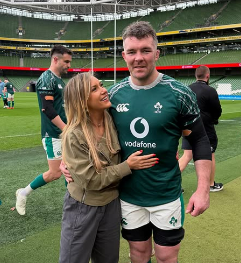 A woman embracing a rugby player in a green jersey.