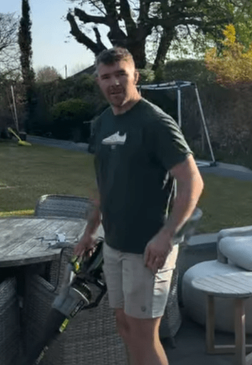Man holding leaf blower in backyard.